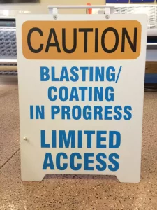 This image shows caution blasting coating sandwich board sign.